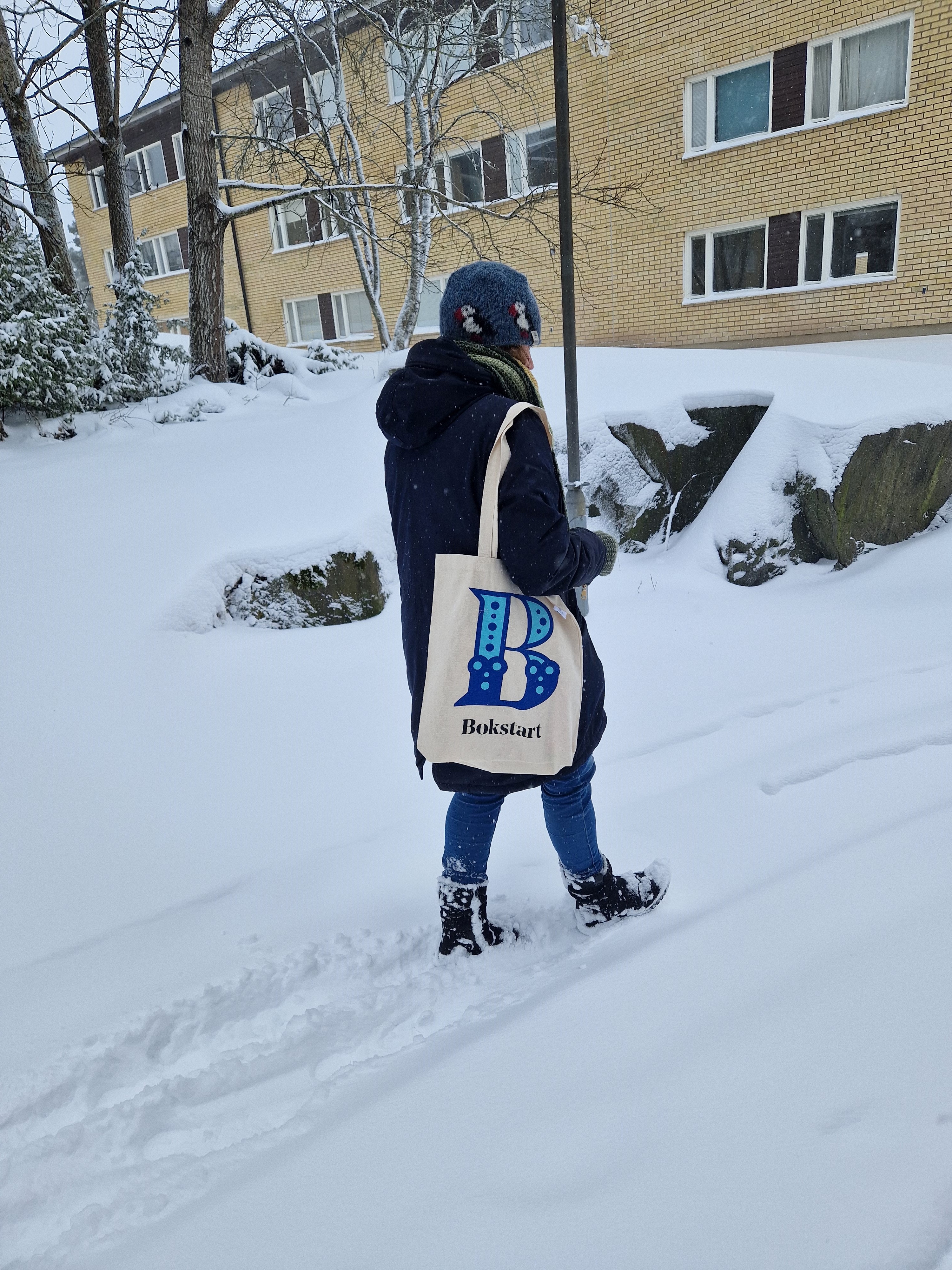 Bokstartare i Sigtuna på väg i snön med Bokstarts tygväska runt axeln.