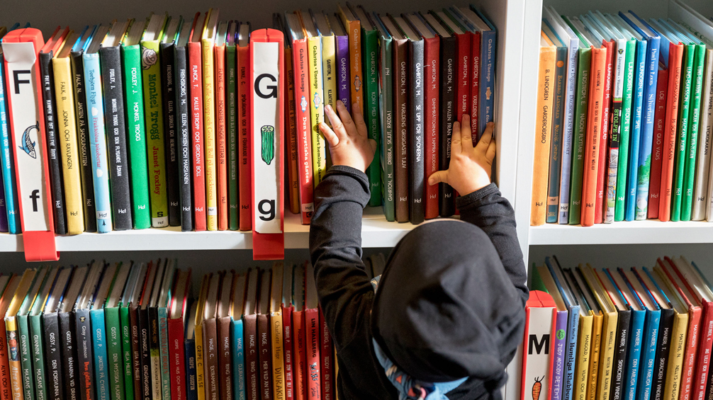 Foto av barn som känner på böcker i bokhylla